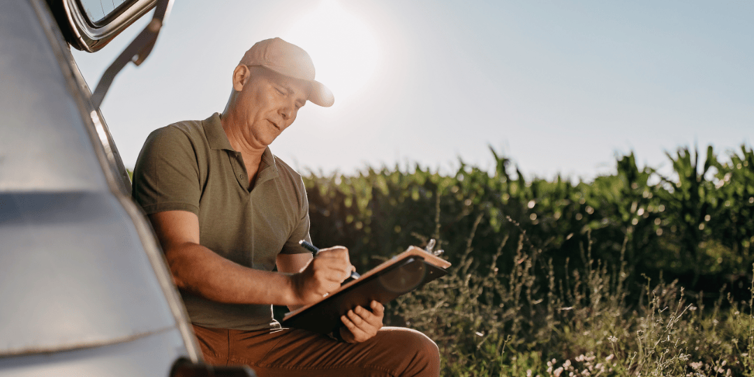 Man in Field Looking at Clipboard