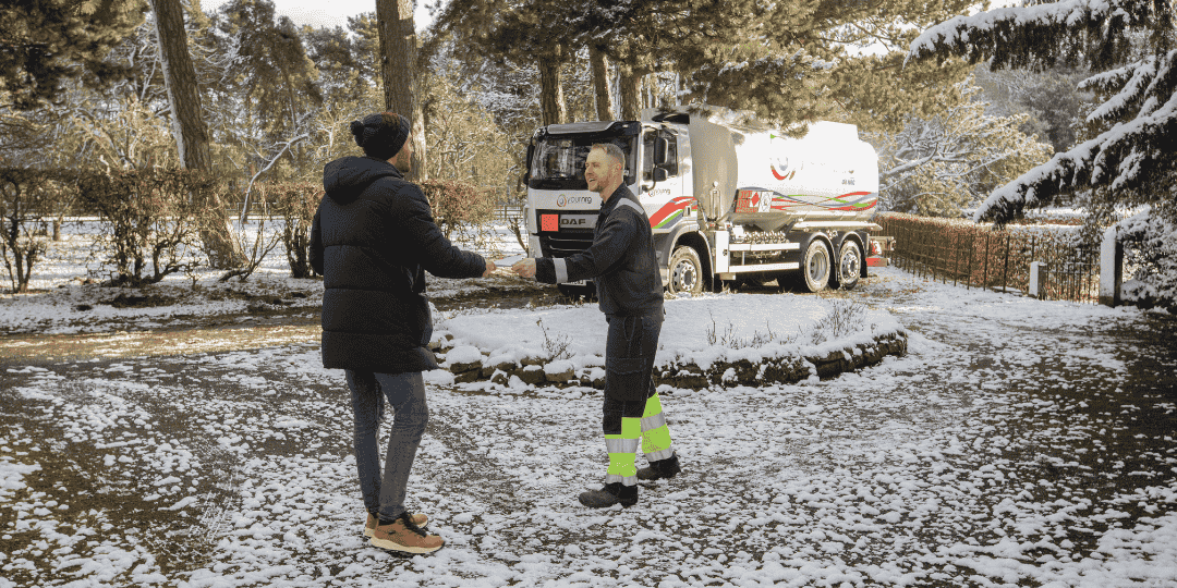 Two Men Stood in the Snow Next To Oil Tanker