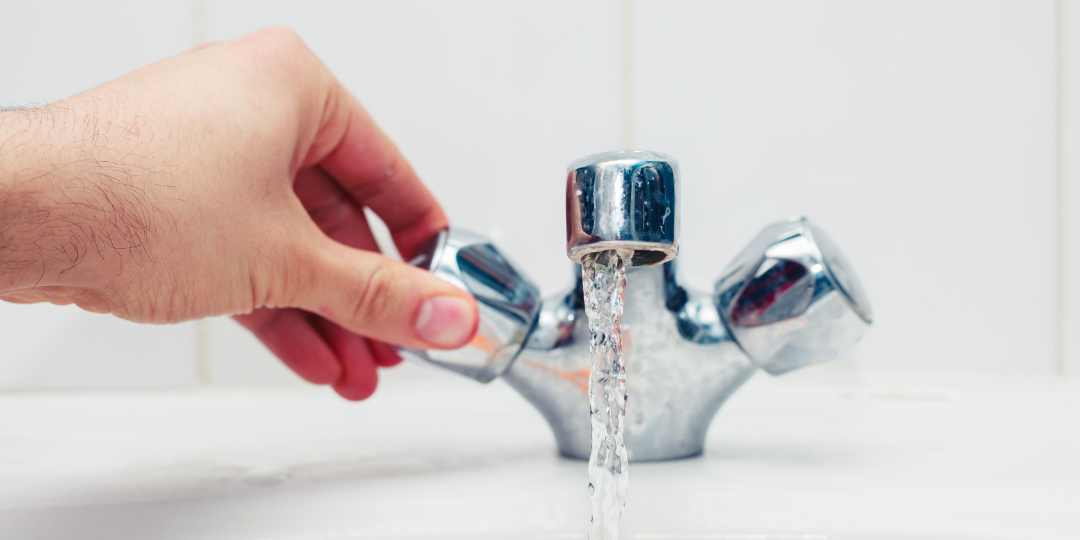 Hand Turning Tap with Water Coming Out